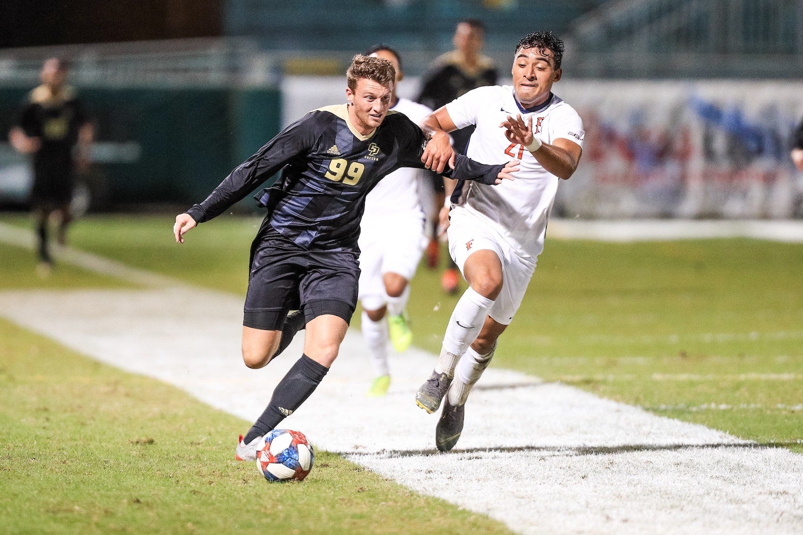 Two student soccer players run for possession of the ball down the field