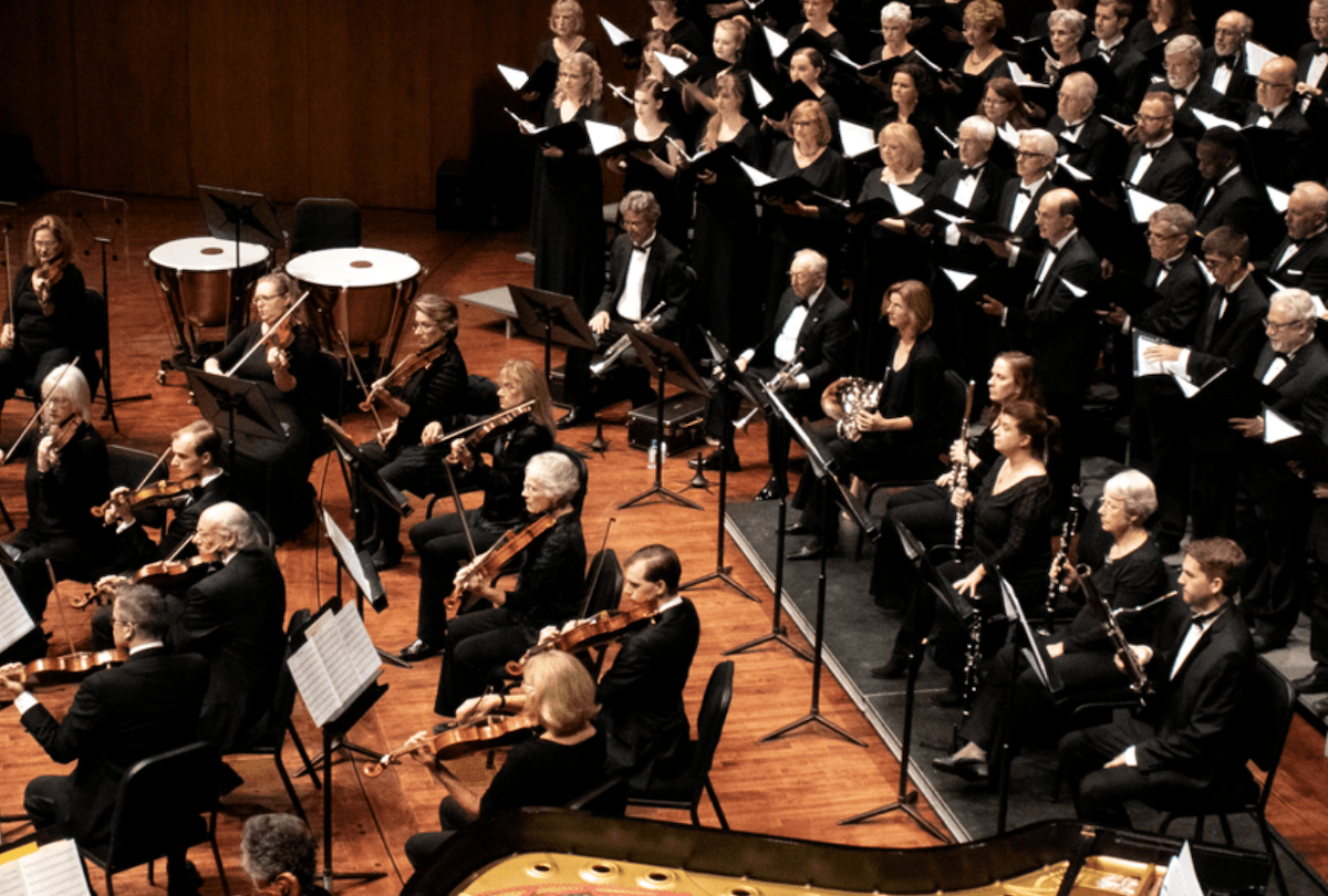 Photo of Master Chorale performance on stage at the PAC with orchestra members. Everyone is dressed in concert black.