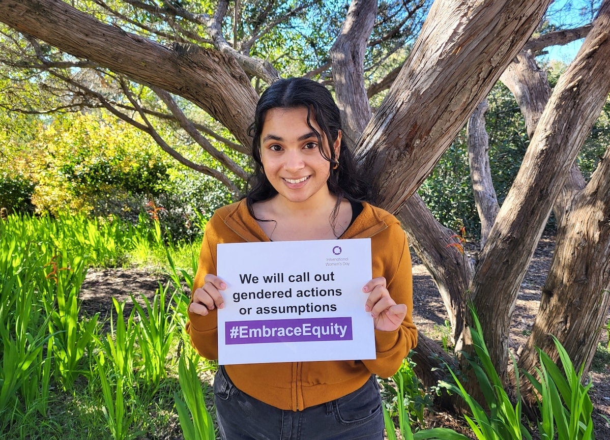 Cal Poly student holding sign the reads, We will call out gendered actions and assumptions