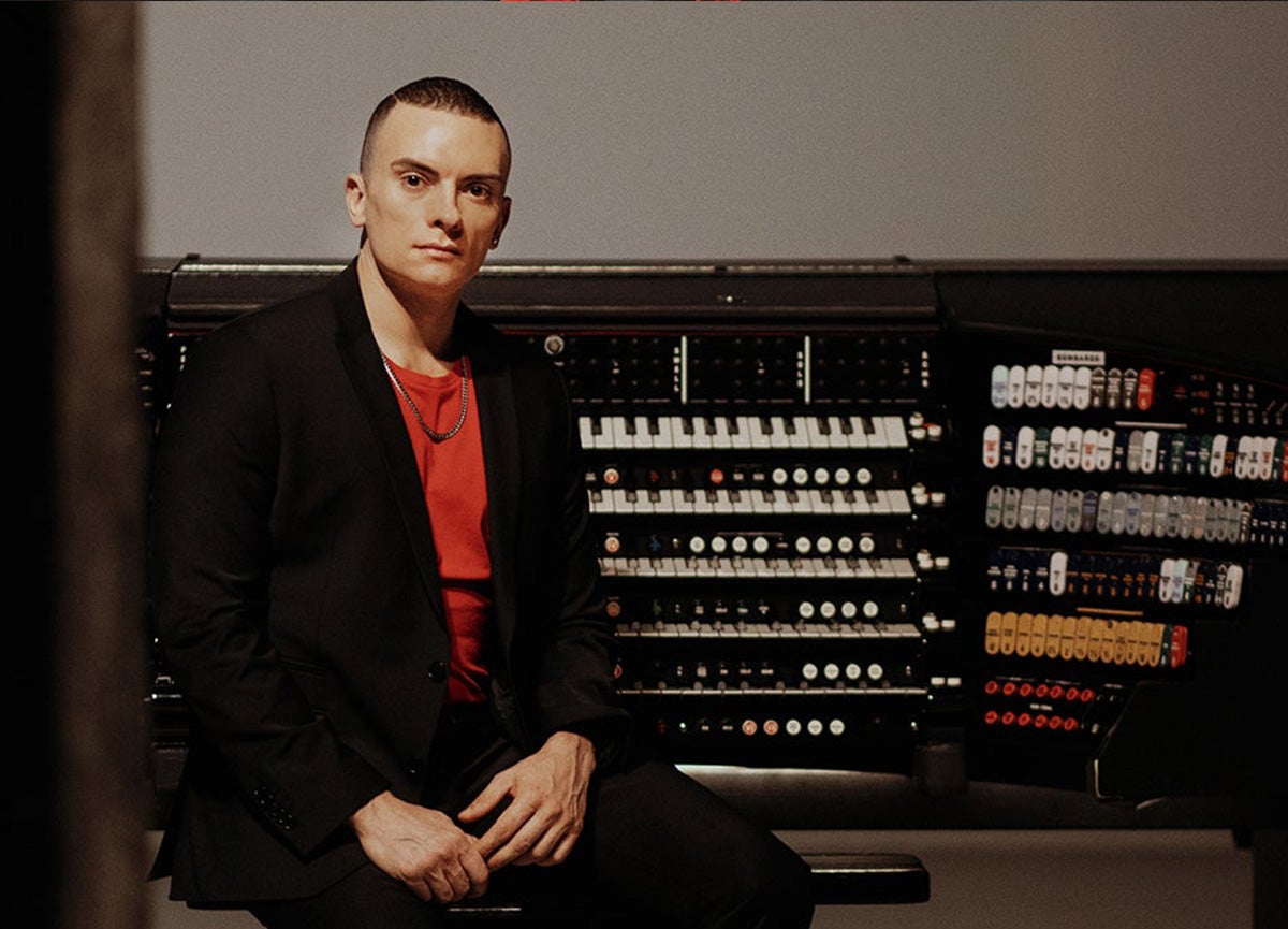 Carpenter photographed in front of organ. 