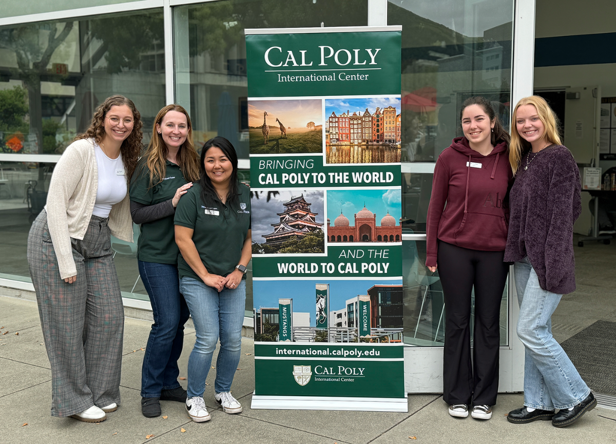 Staff and students gather around signage for Passport event.