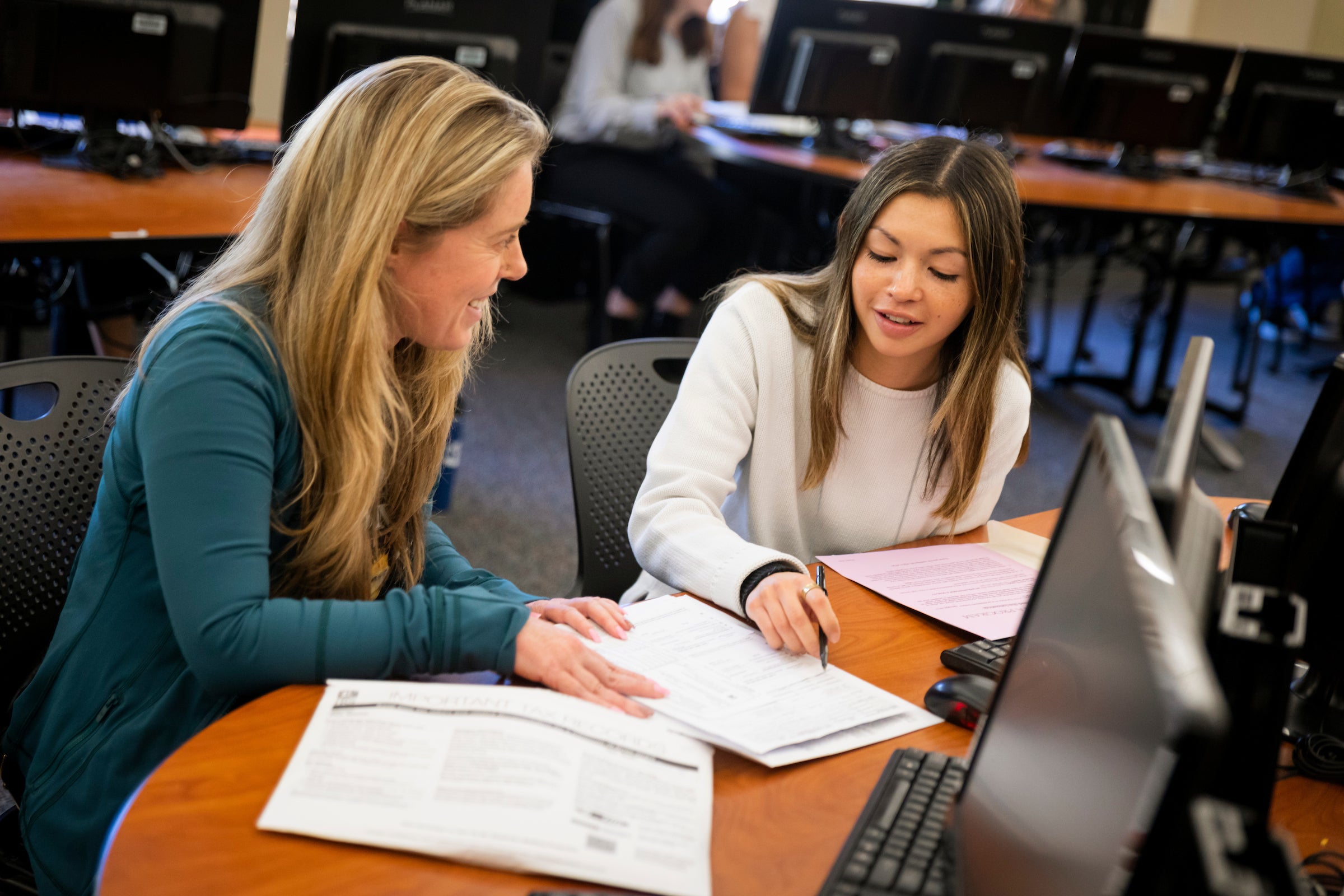 Student and faculty member review paperwork on desk.