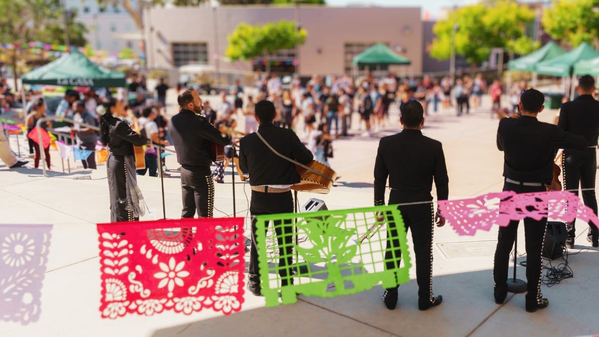 Papel Picado and Latine country flags fly in front of a Mariachi performance on UU Plaza Stage from 2024 HSI Symposium