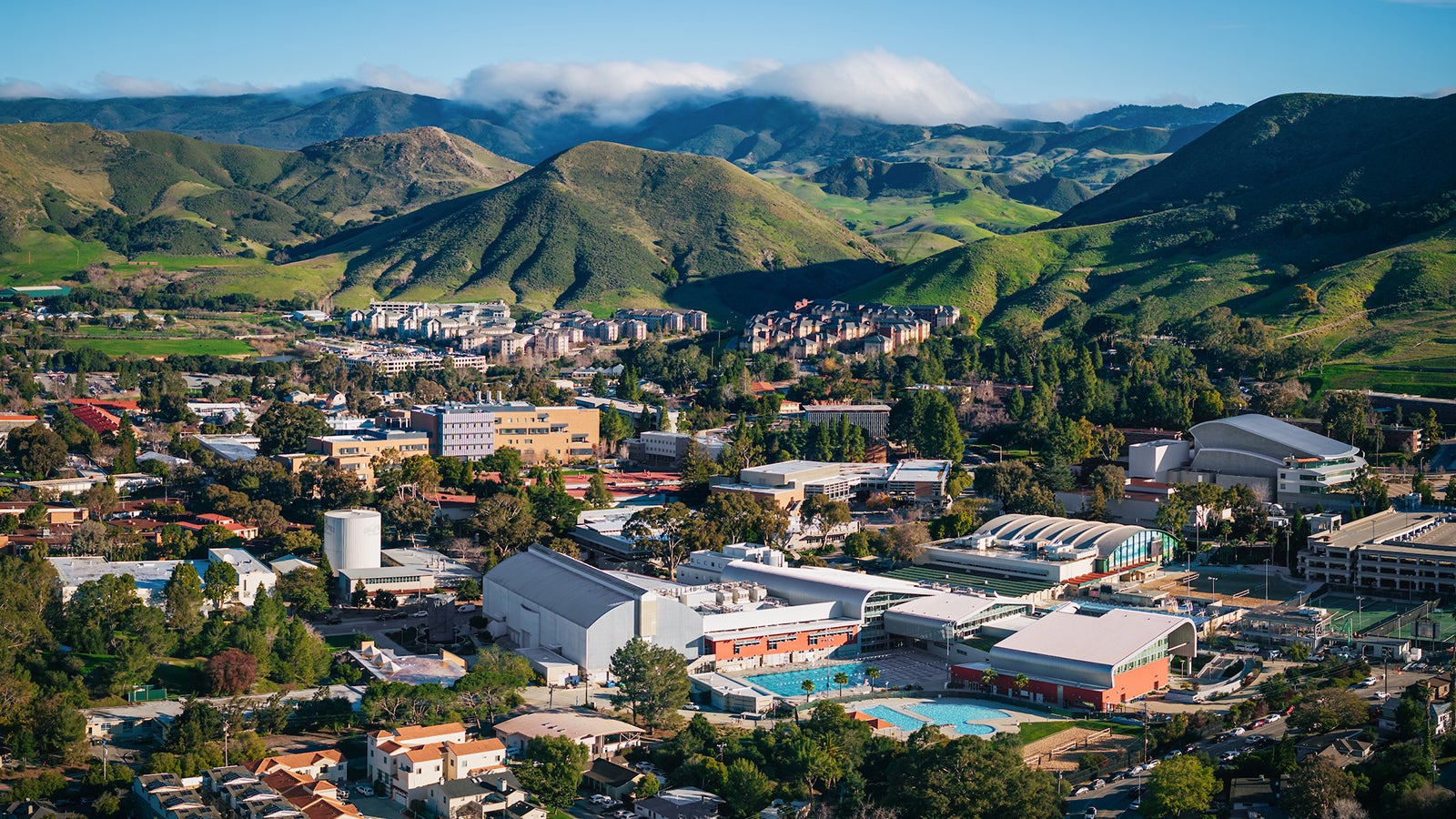An aerial view of the Cal Poly campus with green hills and a blue sky.