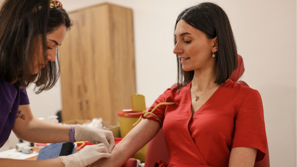 A phlebotomist taking blood from a donor.