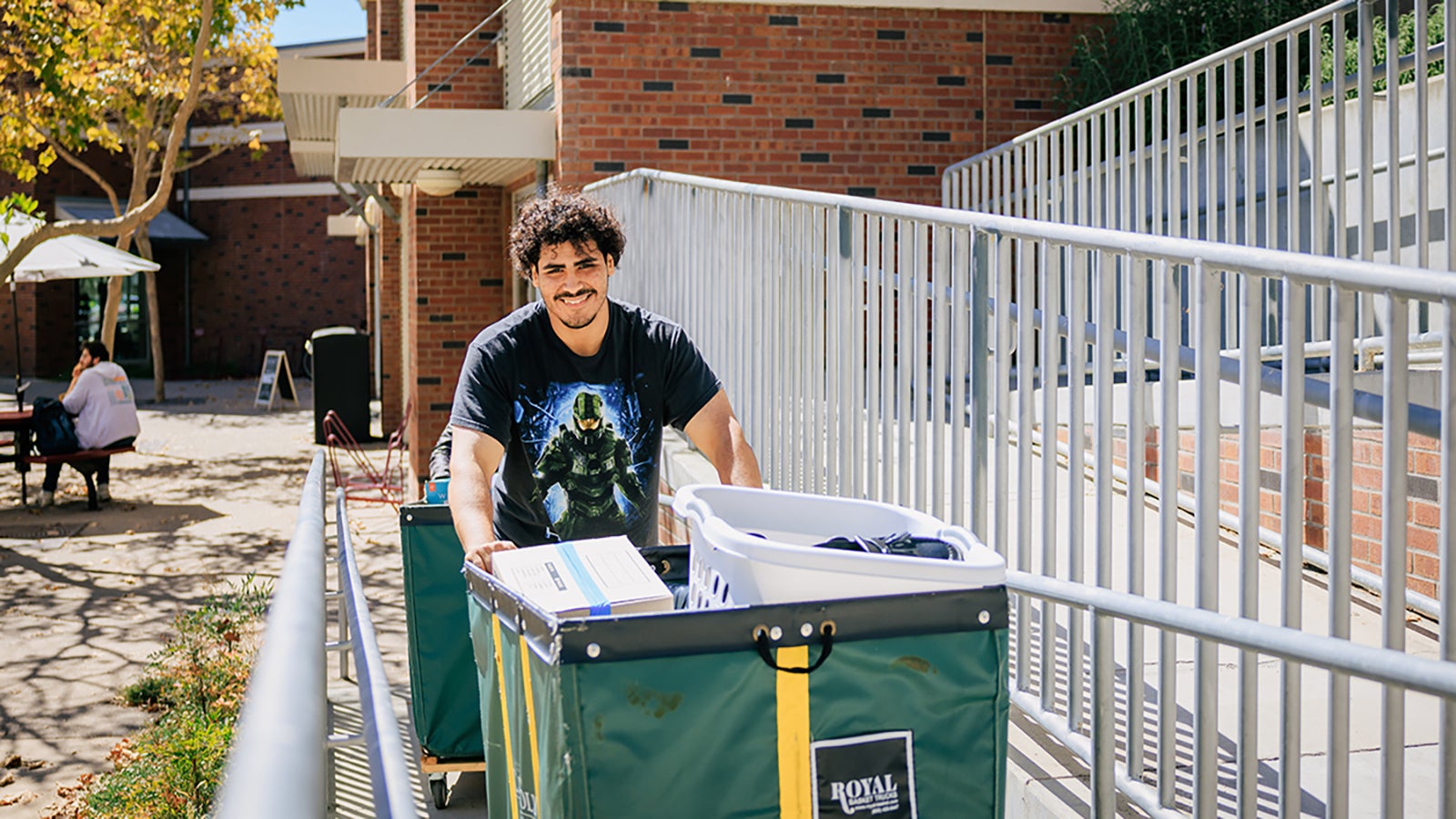 A student pushing a big cart of personal belongings up a ramp into a dorm.