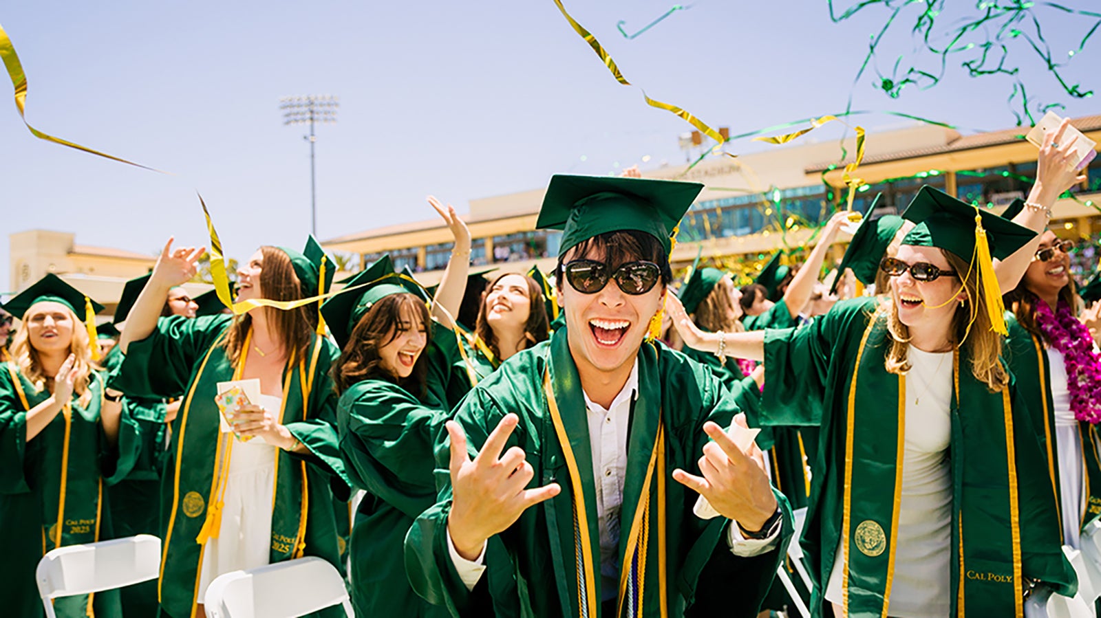 Students celebrating commencement in Alex Spanos Stadium with streamers flying overhead.