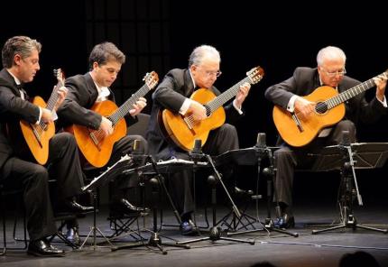 Photo of the Romeros Quartet seated and playing on stage 