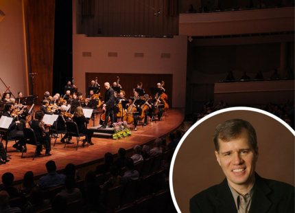 Symphony performs on stage with an image of John Novacek inset on the image.