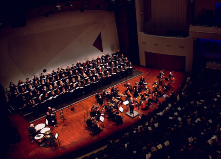 Choir and orchestra perform on stage.