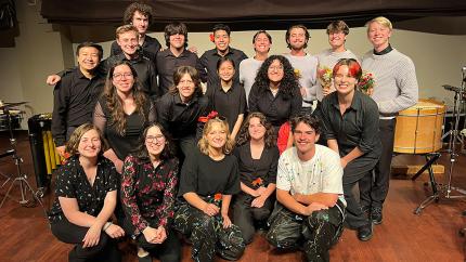 A group photo of PolyRhythmics with instruments in the background.