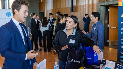 A student talking to a potential employer at a career fair booth.