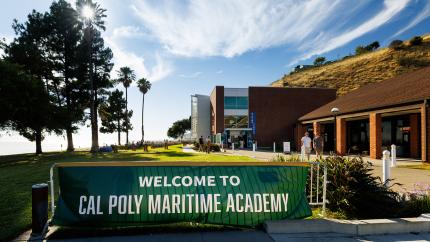The main Cal Poly Maritime Academy sign on the Solano Campus with buildings and people in the background.