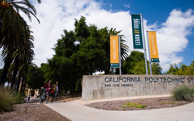 Photo of two people walking next to California Polytechnic University sign 