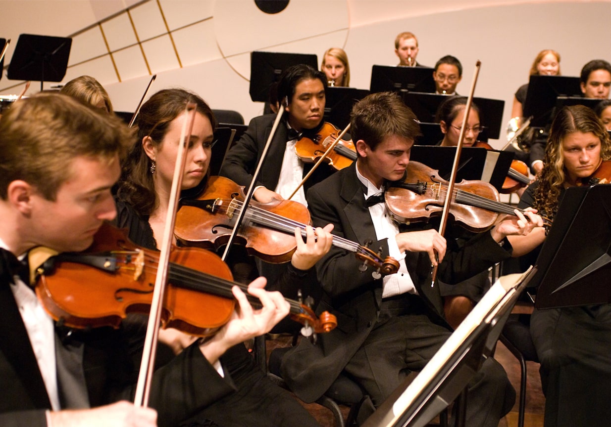 Photo of the violin section of the Cal Poly Symphony in concert dress