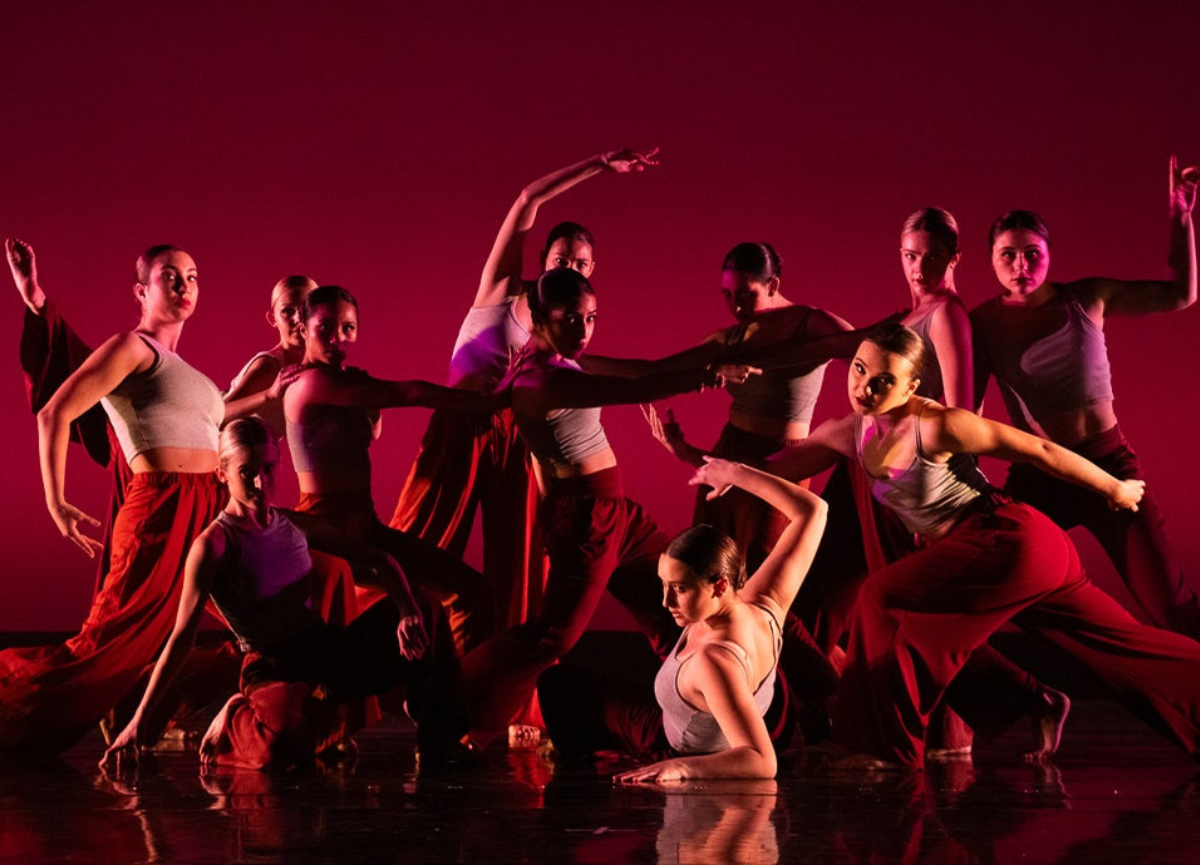 Dancers on stage with red and purple lighting.