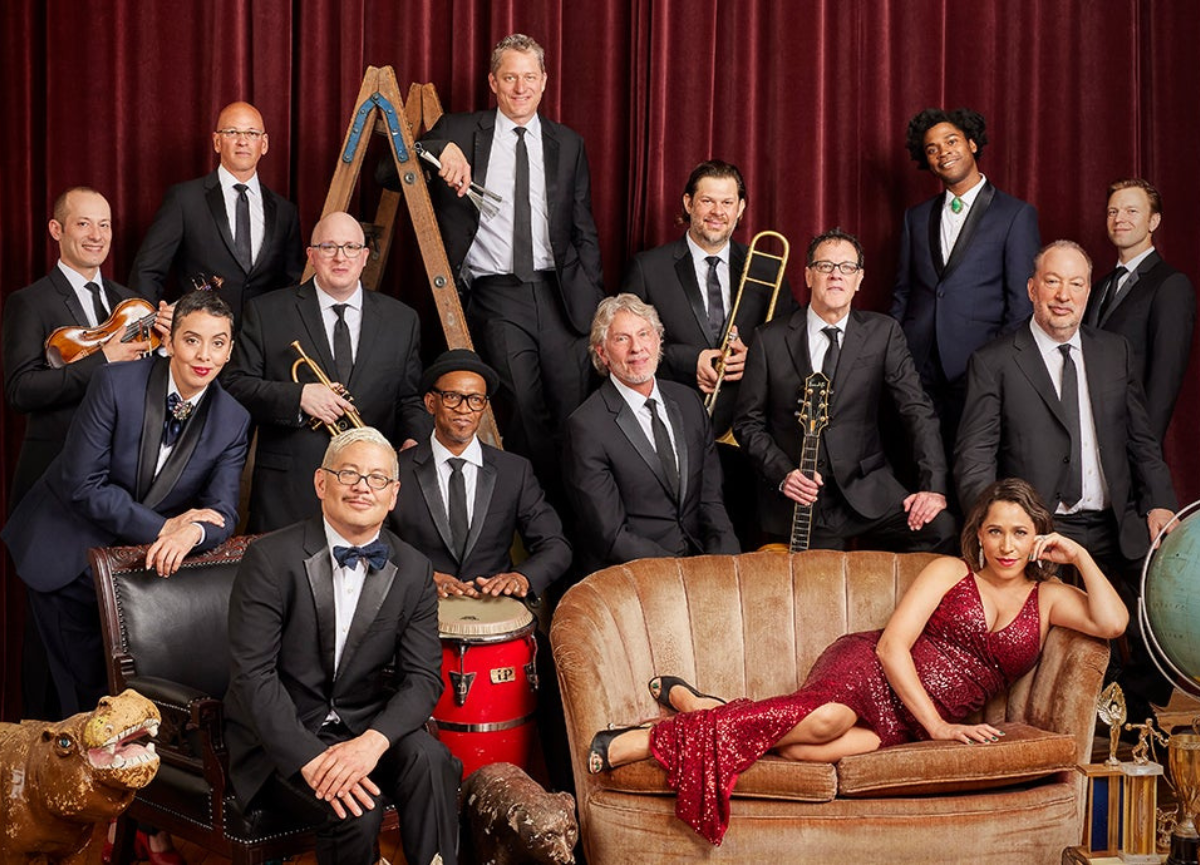 Band with a woman in a sequin red dress sitting on a sofa.