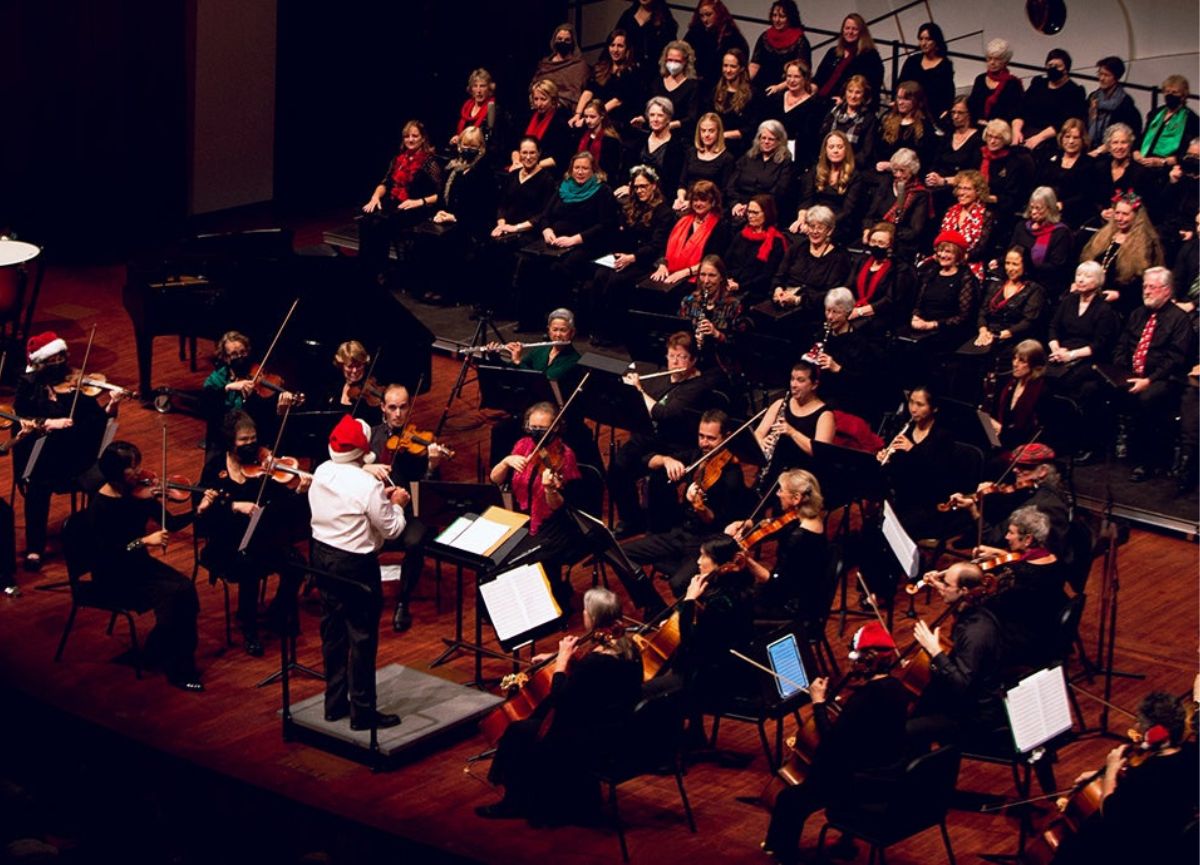 Master Chorale plays on stage with conductor wearing a Santa hat.